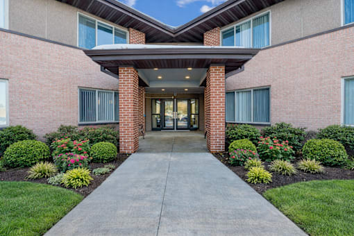 A building entrance with a concrete pathway and a brick pillar.