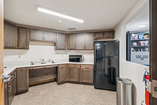 A kitchen with a black refrigerator and wooden cabinets.