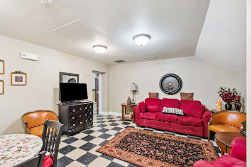 A living room with a red couch and a checkered floor.
