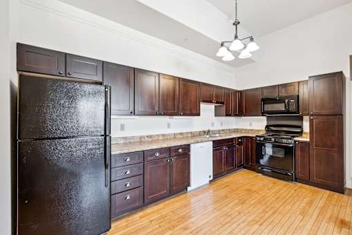 A kitchen with dark wood cabinets and a black refrigerator.