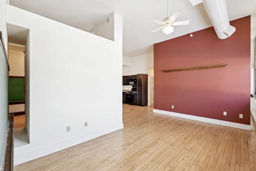 A room with a ceiling fan and a red wall.
