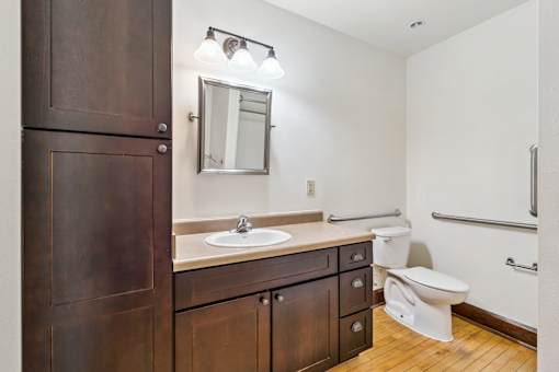 A bathroom with a sink, toilet, and mirror.