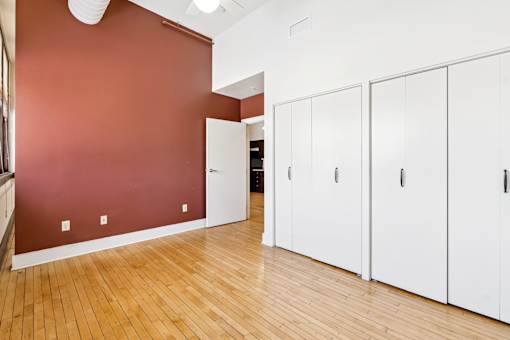 A room with white cupboards and a red wall.