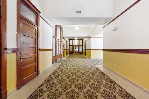 A hallway with a patterned carpet and wooden doors.