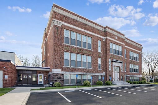 A large red brick building with a parking lot in front.