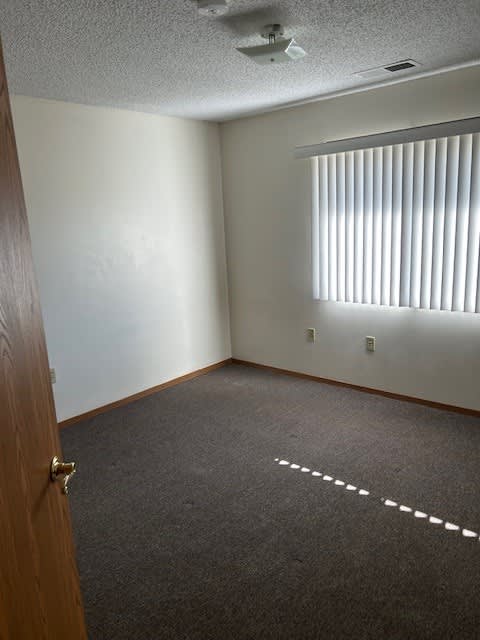 A room with a carpeted floor and a door on the left.