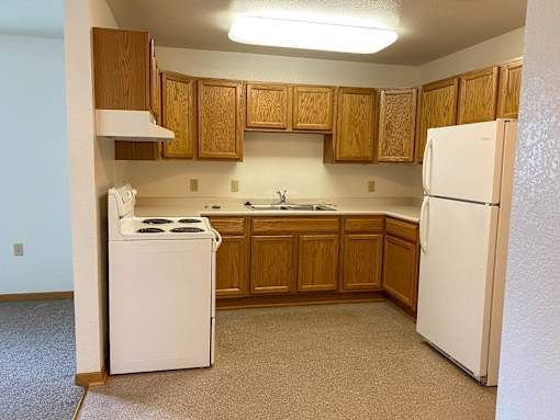 A kitchen with white appliances and wooden cabinets.