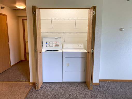 A small white fridge and dishwasher are in a small room.