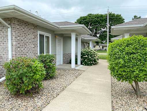 A residential area with a house, bushes, and a gravel path.