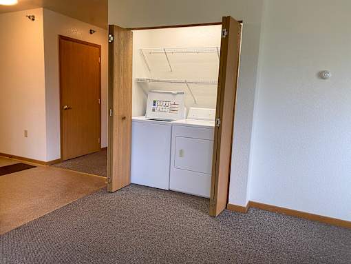 A white cabinet with a drawer is in a room with a brown carpet.