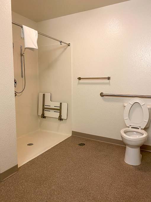 A white toilet in a small bathroom with a towel rack and a towel hanging on the towel rack.