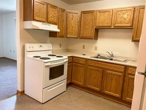 A white stove and oven in a kitchen with wooden cabinets.
