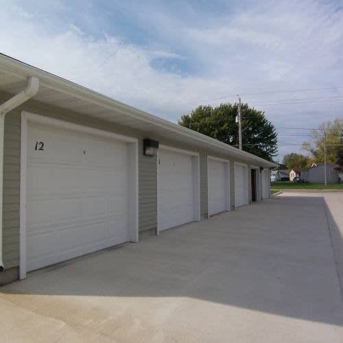 A row of white garage doors are closed and numbered 12.