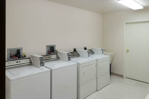 A white room with a row of washing machines.