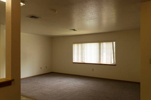 A room with a window and carpeted floor.