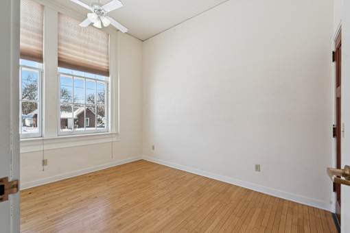 A room with a ceiling fan and a window with blinds.