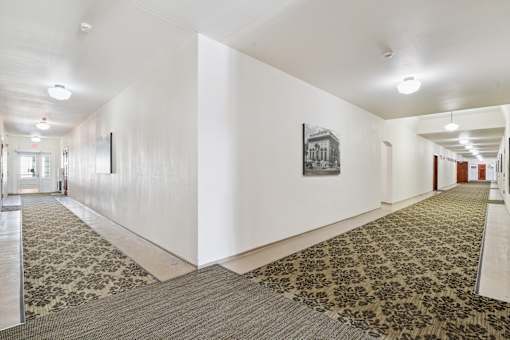 A hallway with a carpeted floor and a picture on the wall.