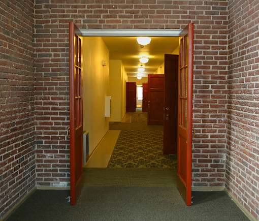 A hallway with a brick wall and a carpeted floor.