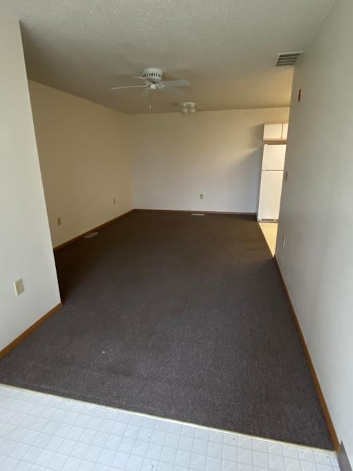 A white laptop is on a white desk in a room with a brown wall.