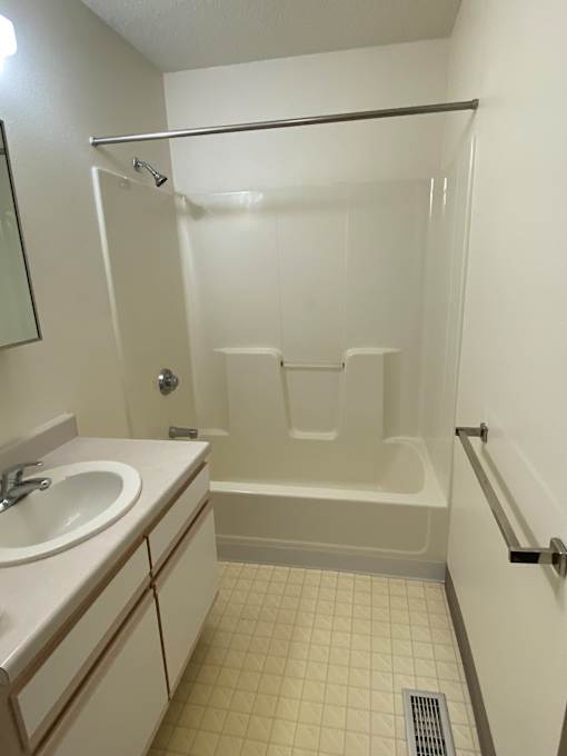 A white bathroom with a glass shower door and a white toilet.