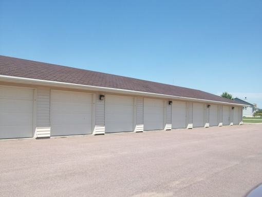 A long building with a brown roof and white garage doors.