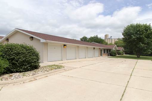 A large garage with a brown roof is surrounded by a concrete driveway.