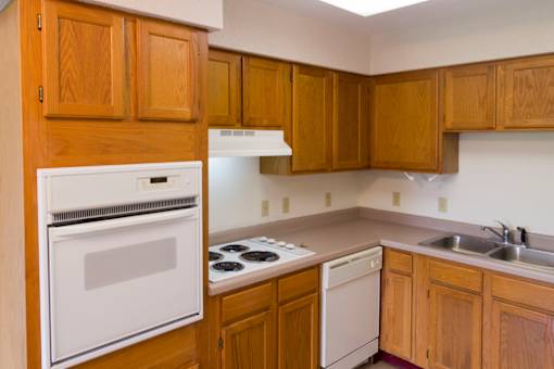 A kitchen with wooden cabinets and a white oven.