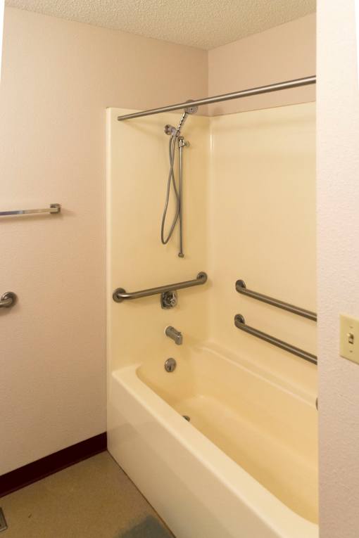A white bathtub with a shower head and hand held shower.