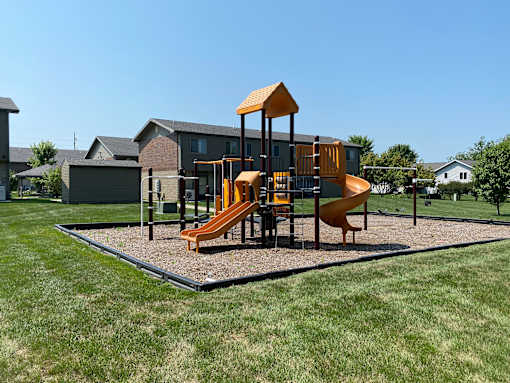 A playground with a yellow slide and a brown structure.
