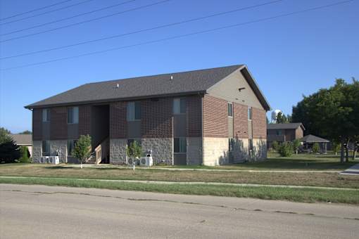 A large brick building with a grey roof and a small porch.