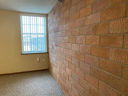 A room with a brick wall and a window.