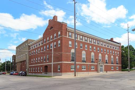 A large red brick building with a parking lot in front.