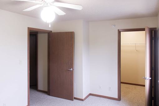 A room with a ceiling fan and two doors.