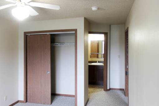 A room with a ceiling fan and a door leading to a kitchen.