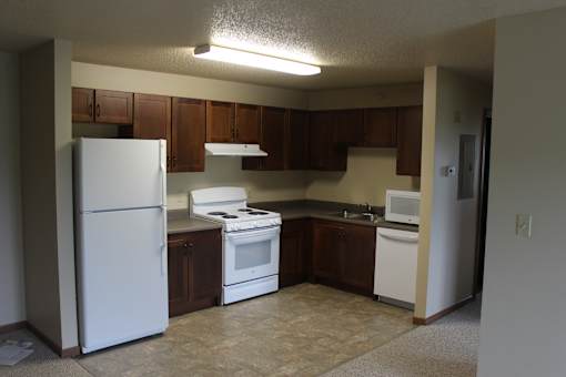 A kitchen with white appliances and brown cabinets.