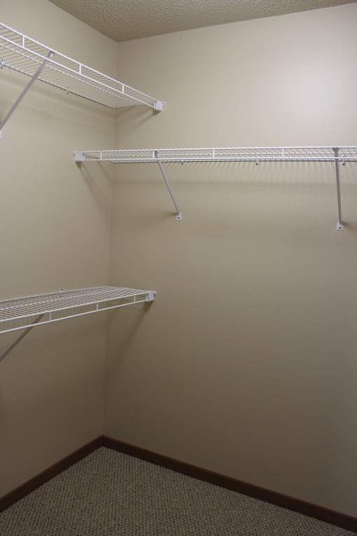 A white shelving unit with three shelves is in a corner.