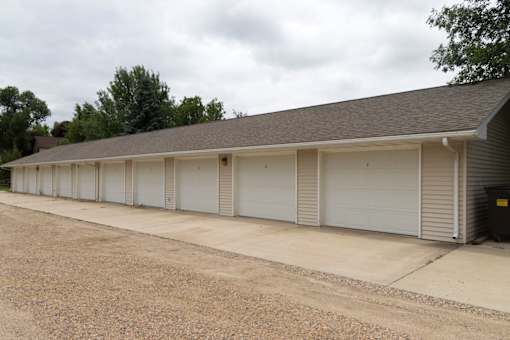 A long building with a grey roof and white garage doors.