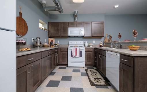 A kitchen with a white dishwasher and a black and white checkered floor.