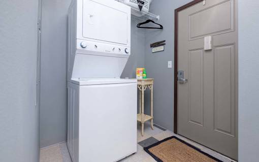 A white refrigerator is in a kitchen next to a brown door.