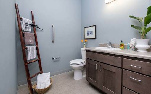 A bathroom with a toilet, sink, and a wooden ladder.