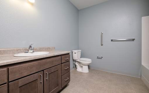 A bathroom with a sink, toilet, and a towel bar.