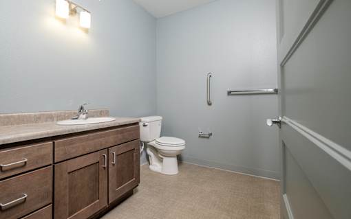 A bathroom with a toilet, sink, and wooden cabinets.