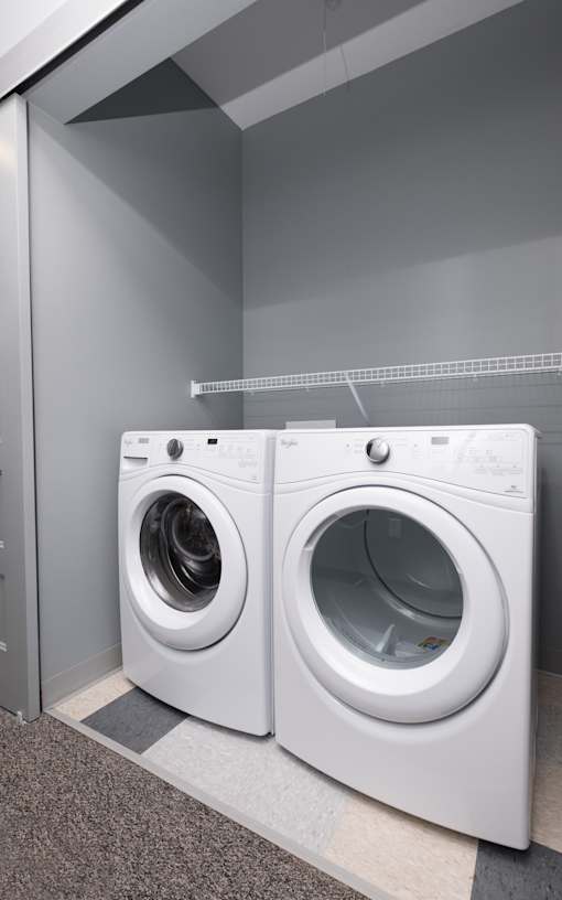Two white front load washing machines in a laundry room.