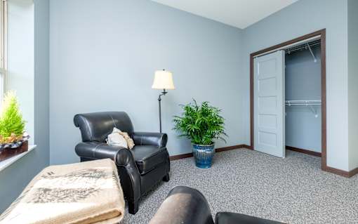 A living room with a black leather chair and a grey couch.