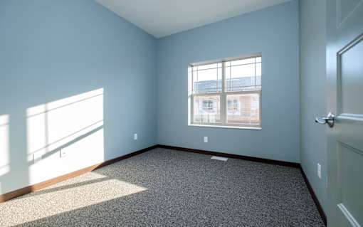 A room with a carpeted floor and a window.