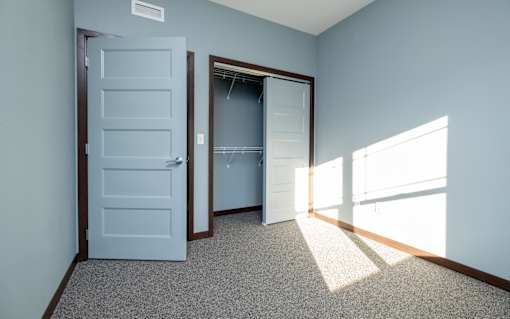 A room with a white door and a carpeted floor.