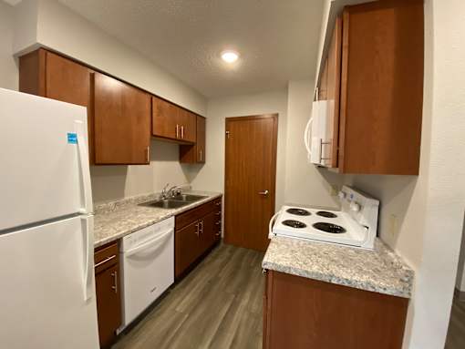 A kitchen with a white stove top oven and white appliances.