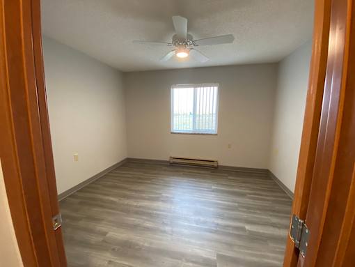 A room with a ceiling fan and a window with blinds.