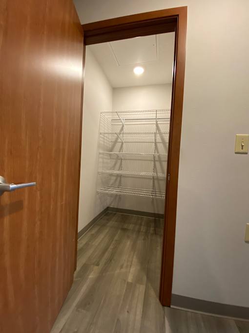 A hallway with a wooden door and a white wall.