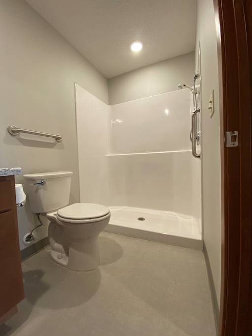 A white toilet sits in a bathroom next to a bathtub.